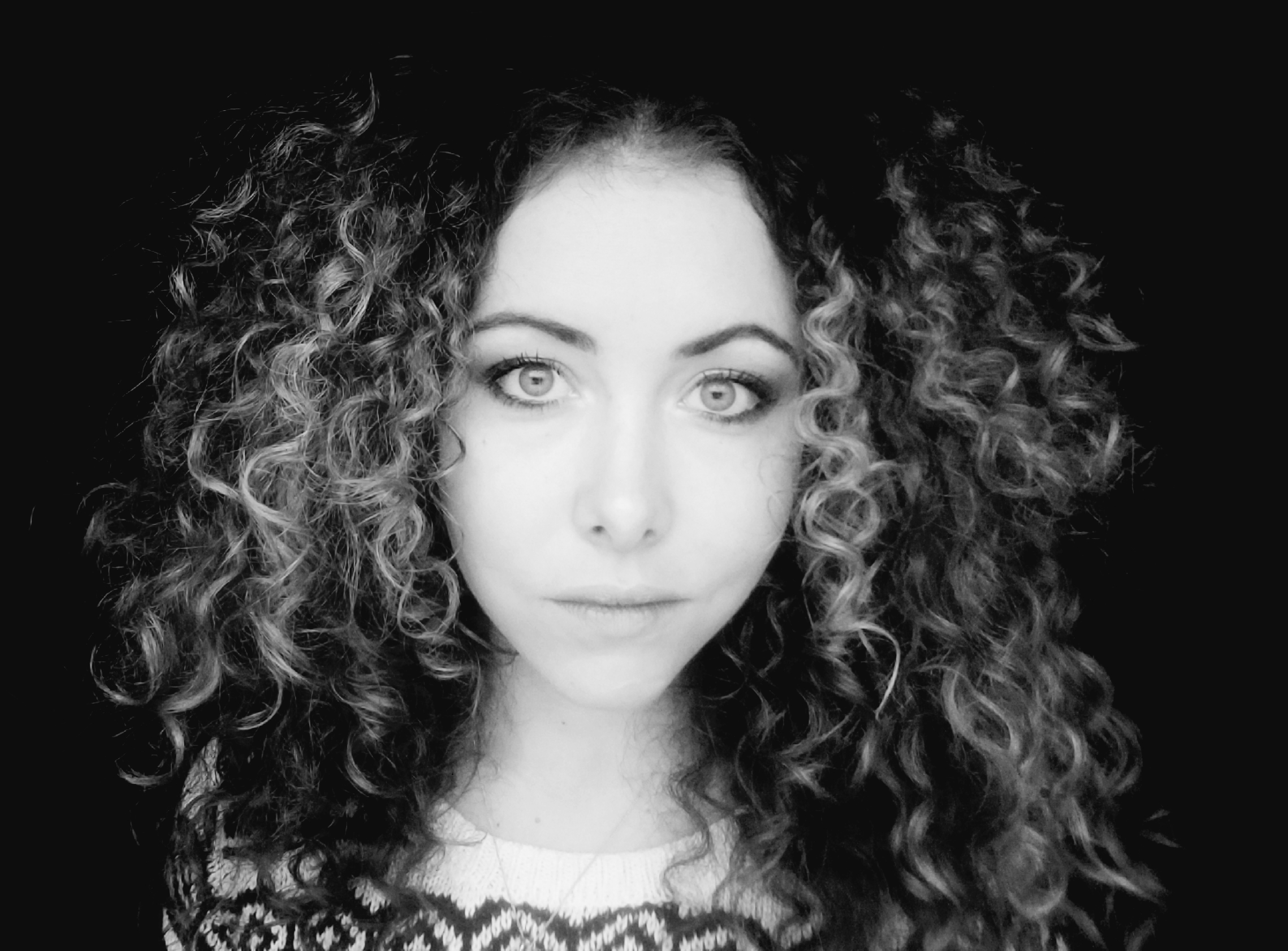 Chelsea Whitton, a white woman with big, curly hair, in a black-and-white closeup.
