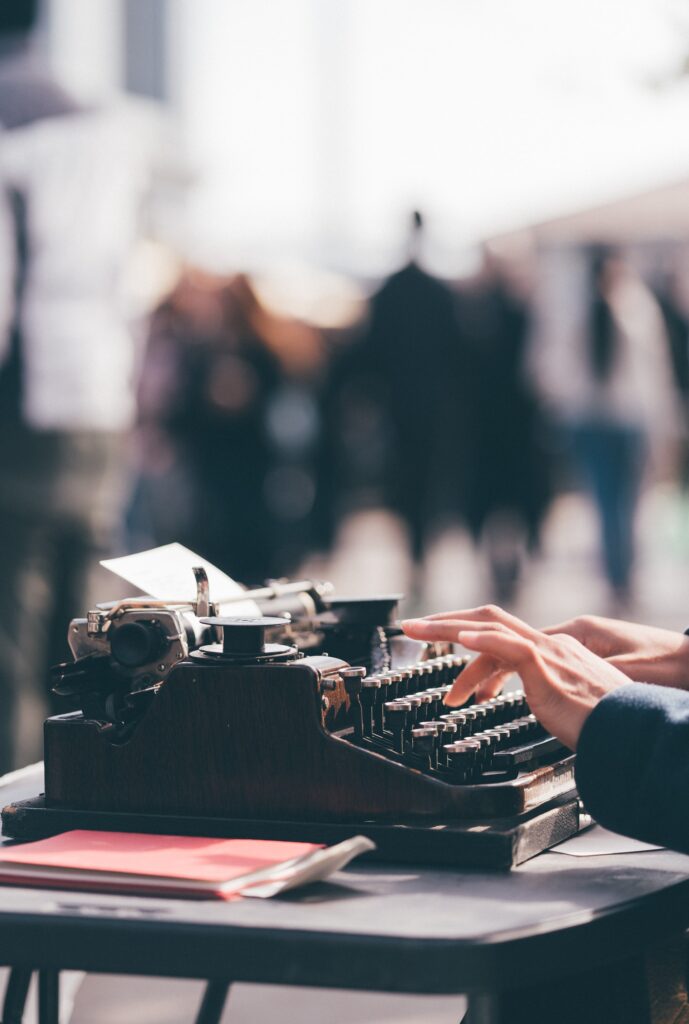 a black typewriter with a pair of white hands typing on it