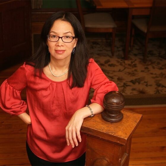 An Asian American woman with long dark hair, and a shiny red blouse.