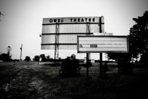 One sign that says Owen Theater, with another in front of it that says CLOSED with a large space between the L and the O