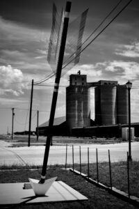 A large sculpture of an arrow, with a silo in the background