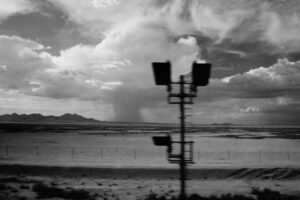 Railroad signal light in the foreground, with a distant storm in the background