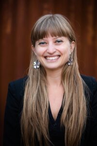 Allison Field Bell, smiling, with long brown hair and a dark top.