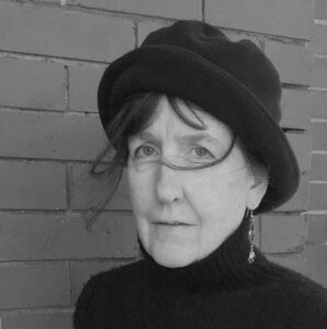 black-and-white image of woman looking into camera wearing a turtleneck and hat