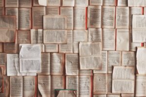 Pages of an old book are tacked up to the wall in an overlapping manner. 