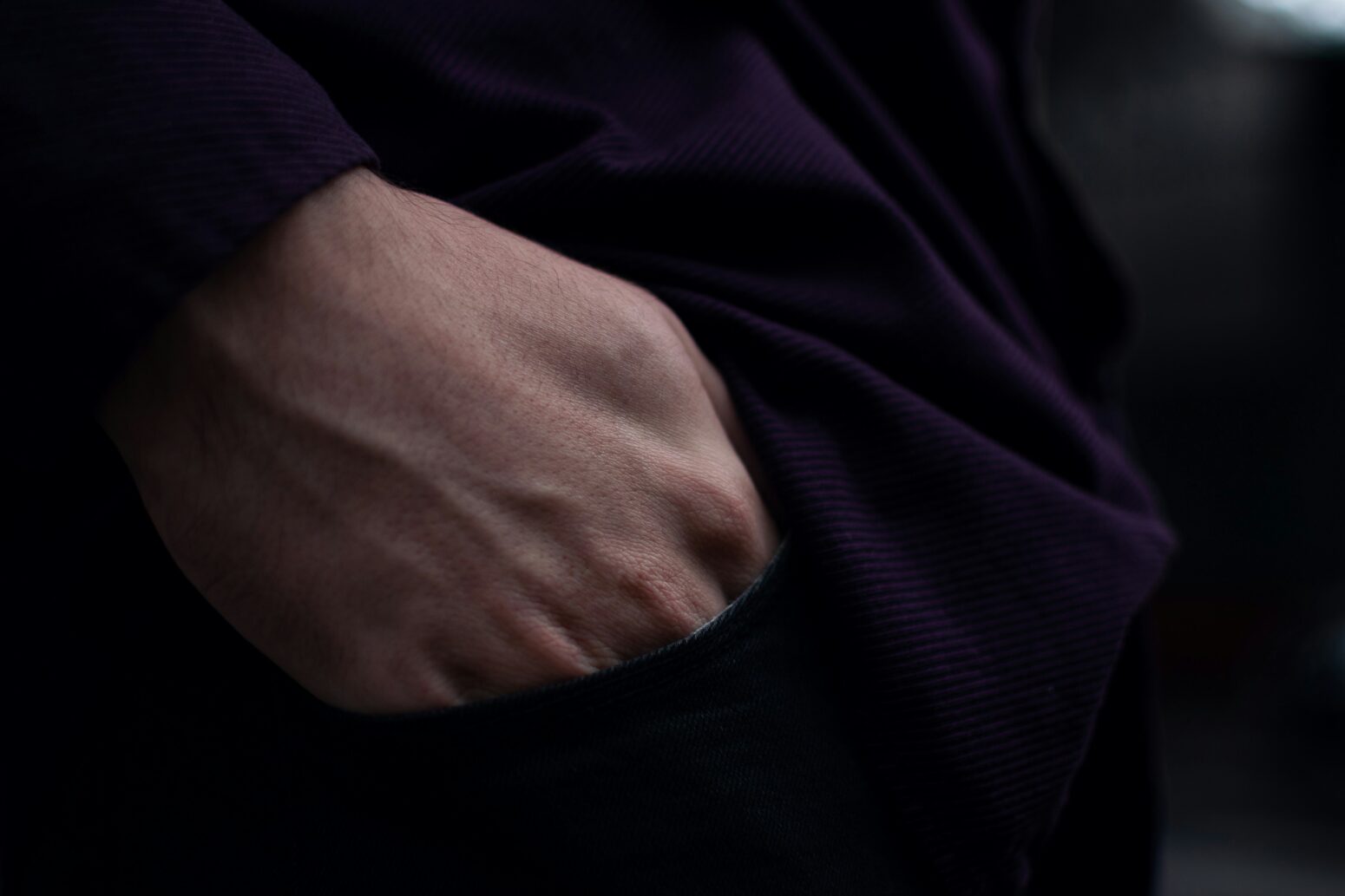Close-up of a hand tucked into a dark coat jacket