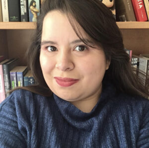 Author Kathryn Diaz stands in front of a bookshelf. 