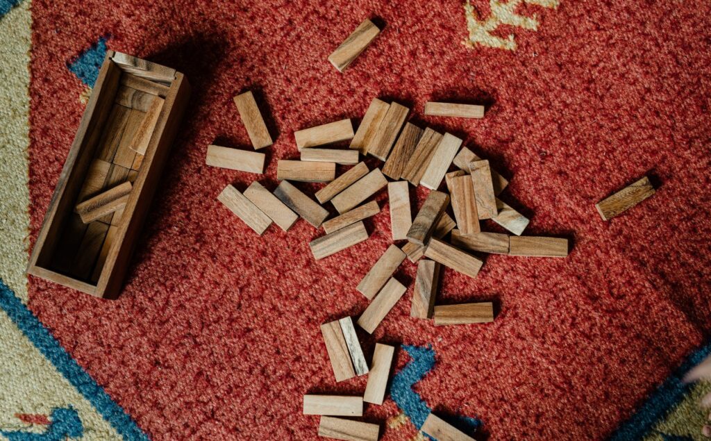 Wooden jenga pieces scattered on e a red carpet
