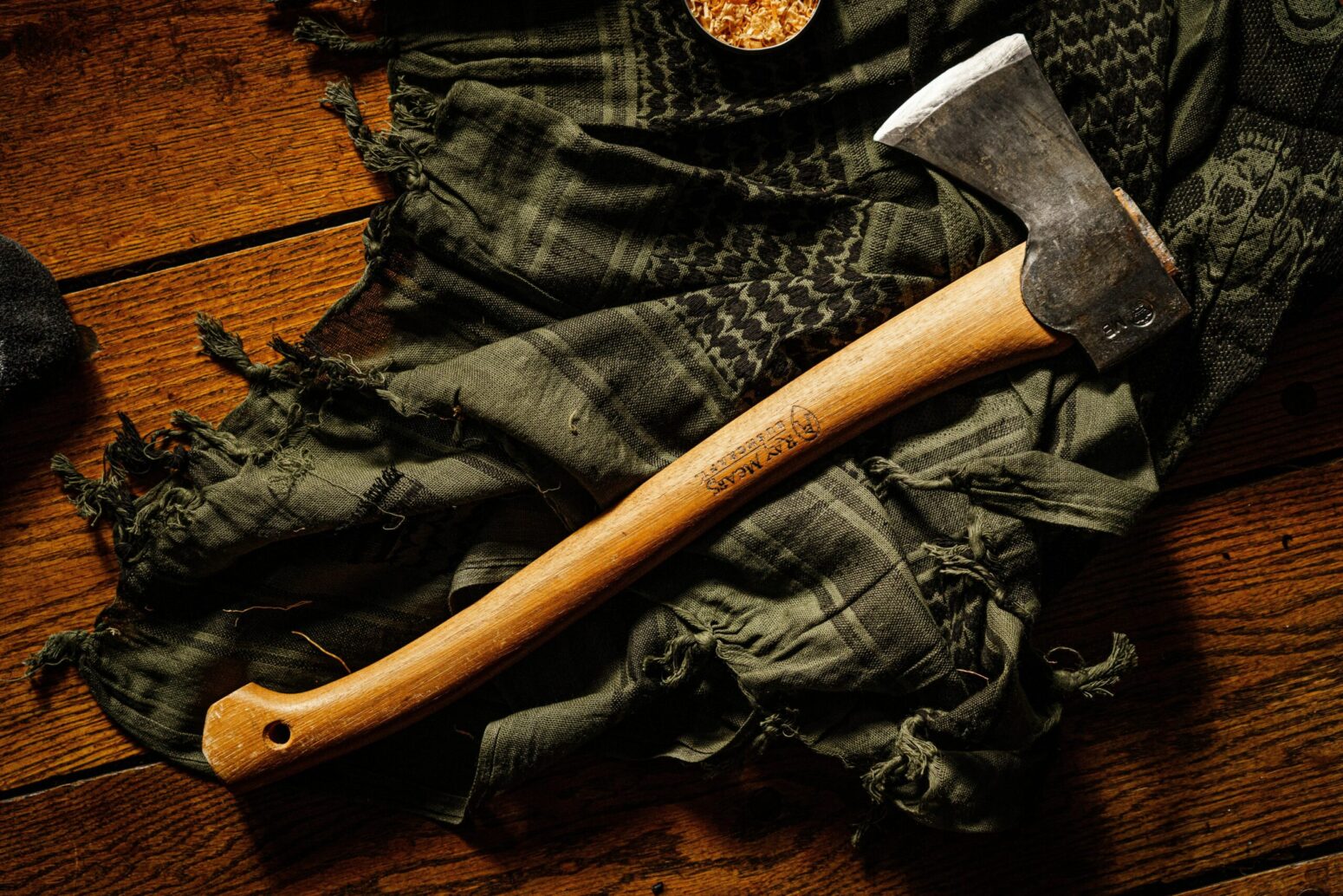 A hatchet laying on top of a green blanket on the floor