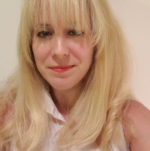 Photo of author, Leah Umansky. She is wearing a white button down tank top and has blonde hair with bangs. 