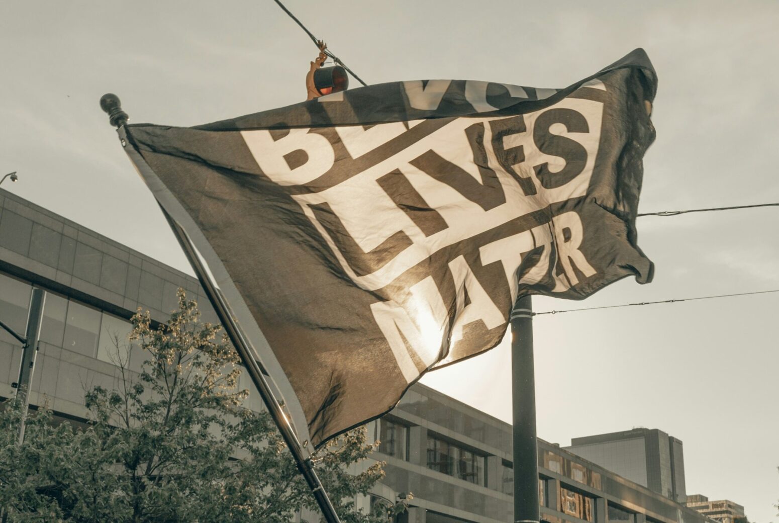 A black-and-white flag waving in the wind that reads "Black Lives Matter."
