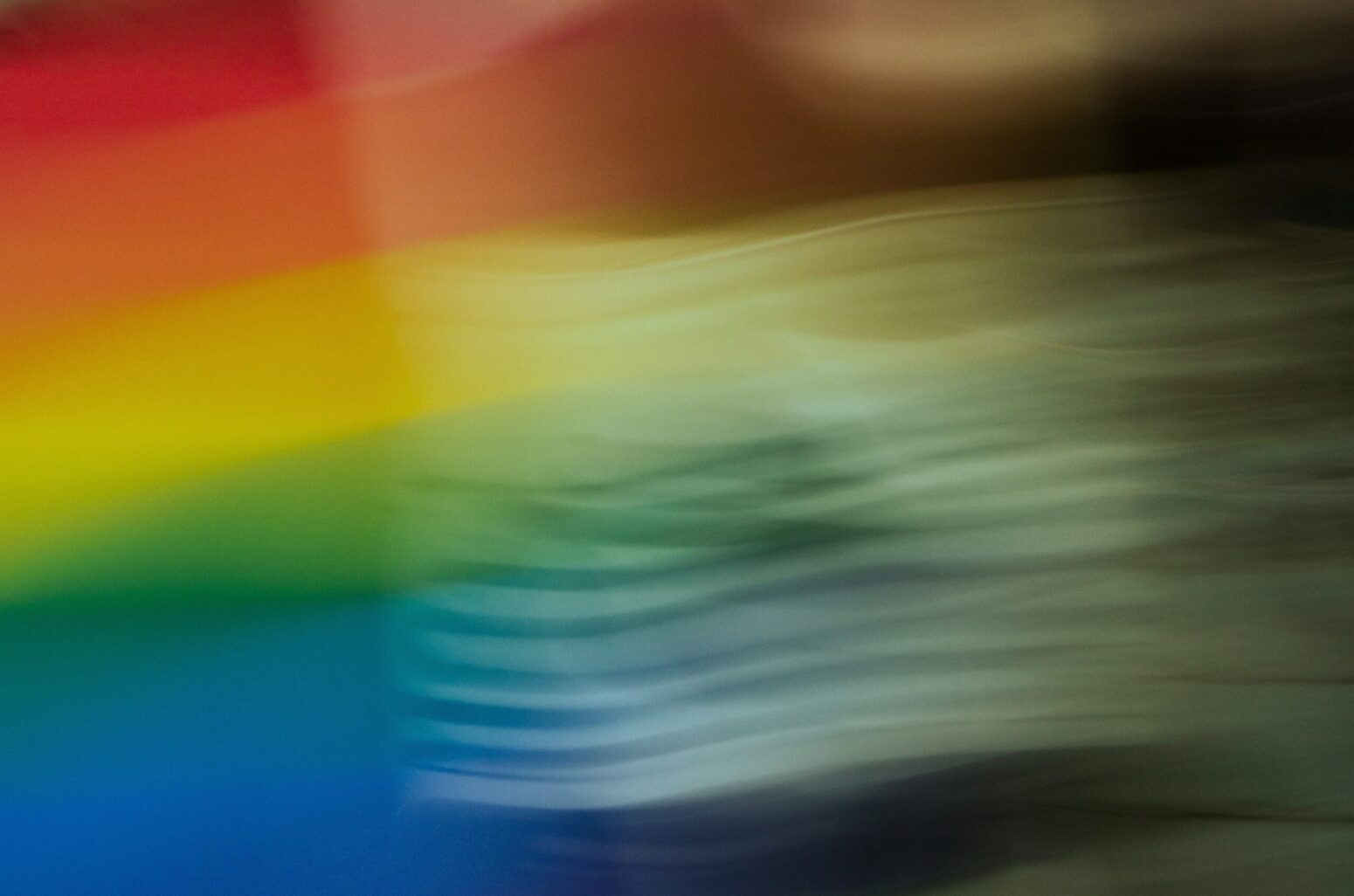 A dark, blurry photo of a rainbow flag