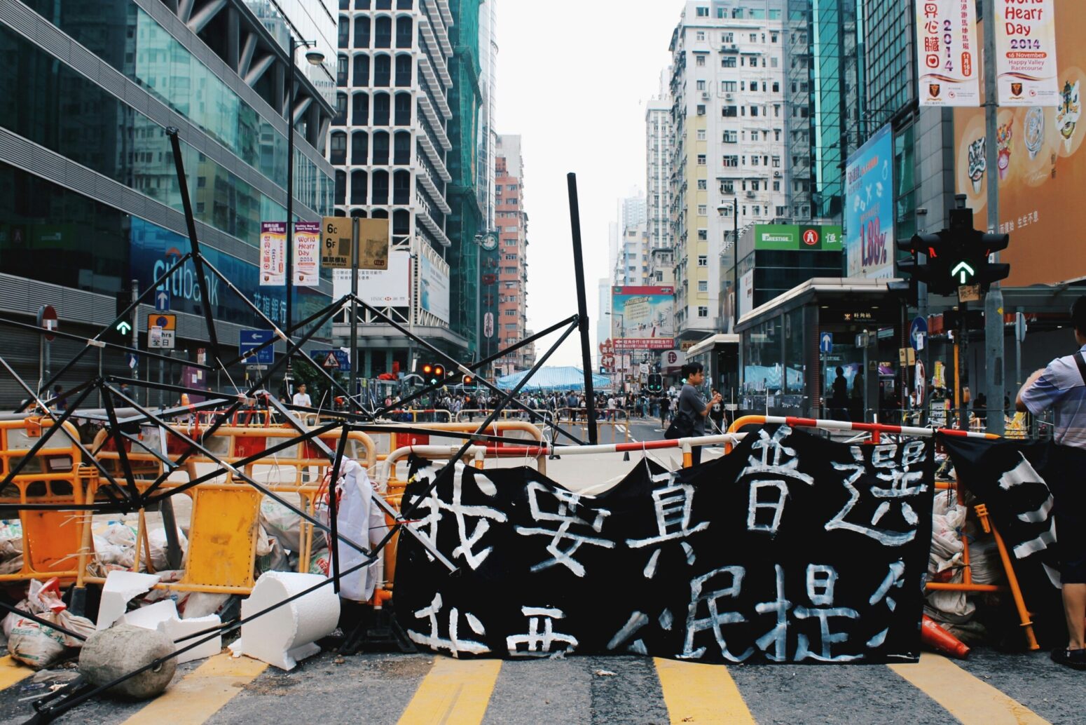 A black banner draped over a make-shift barricade on a city street that reads "I want true universal suffrage provided by Chinese citizens" in Chinese.