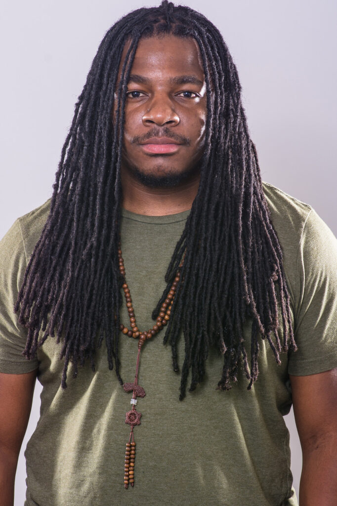 Photo of author against a gray background, wearing a green shirt and looking straight into the camera