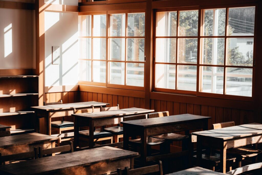 Light falling through windows onto wooden schoolroom desks.