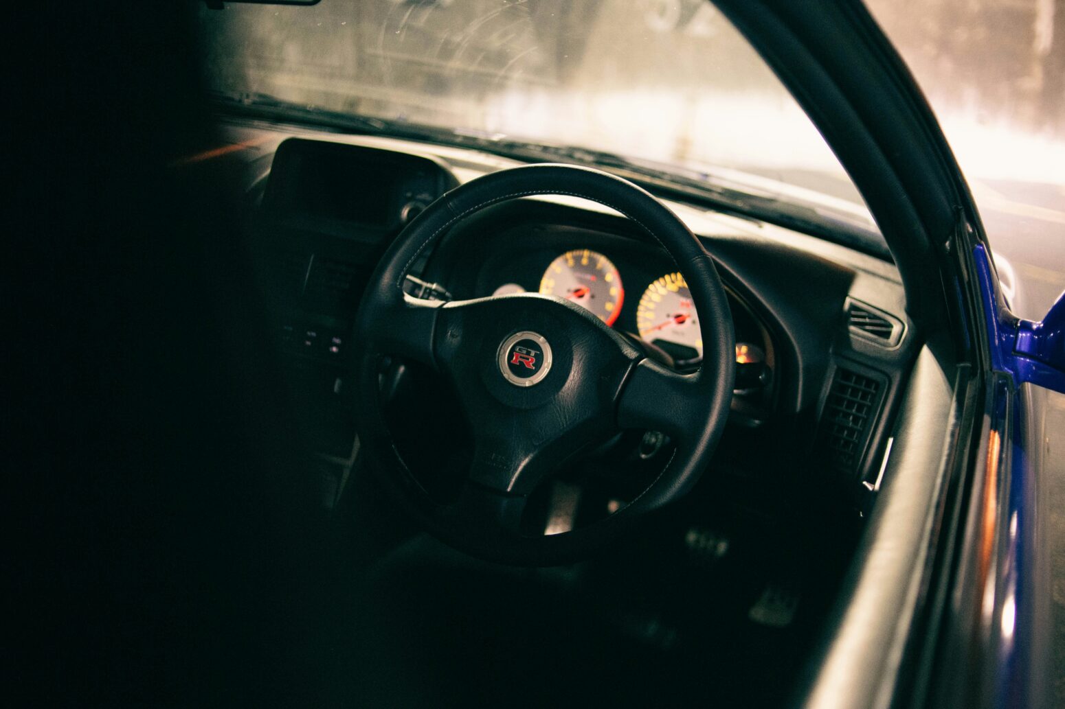 Close up on a car's steering wheel and dashboard, with some gauges lit up