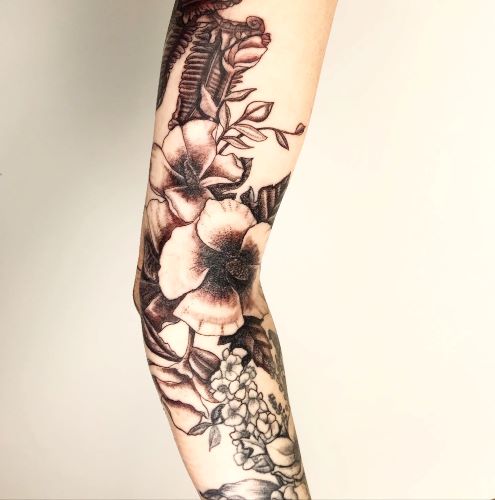 A tattoo of a collection of flower petals and buds on an inner-arm