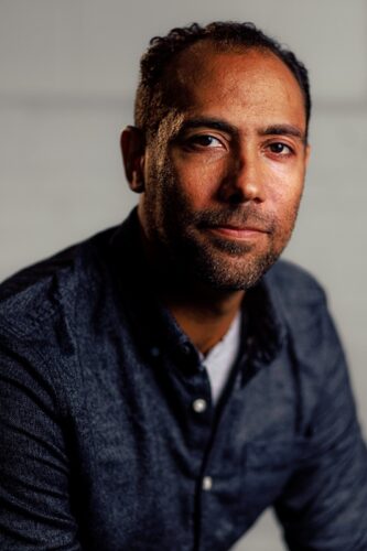 James Stewart III, a Black man in a blue button-up shirt over a white T-shirt.