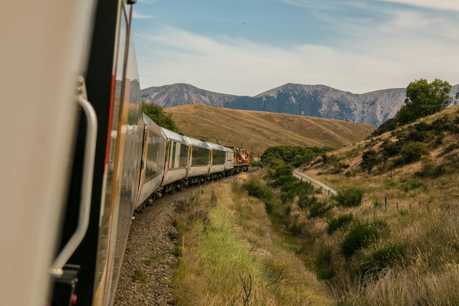 A train works its way around a curve, with mountains in the distance.