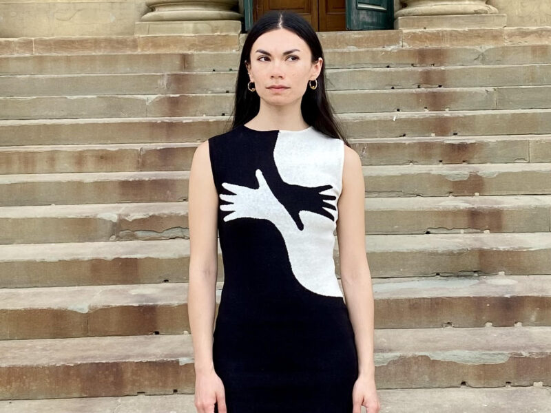 Sarah Chin, pictured in front of a flight of a stairs. Chin is wearing gold hoop earrings and a black and white graphic dress.