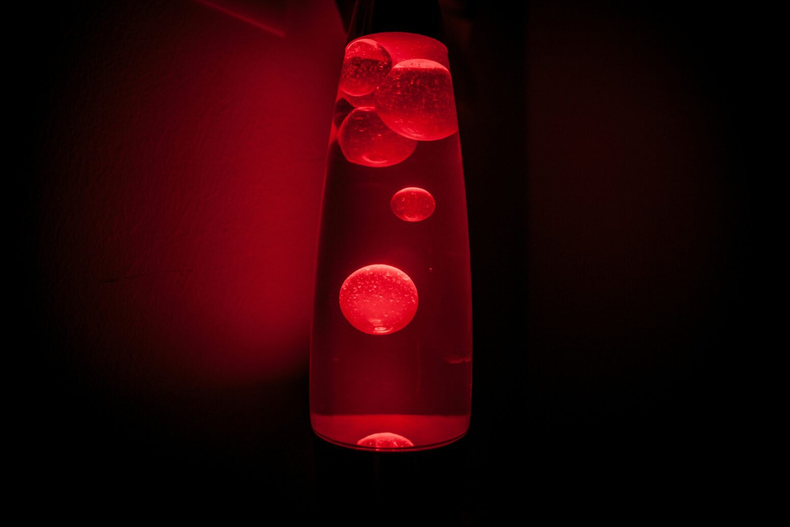 A red lava lamp glows in the dark.