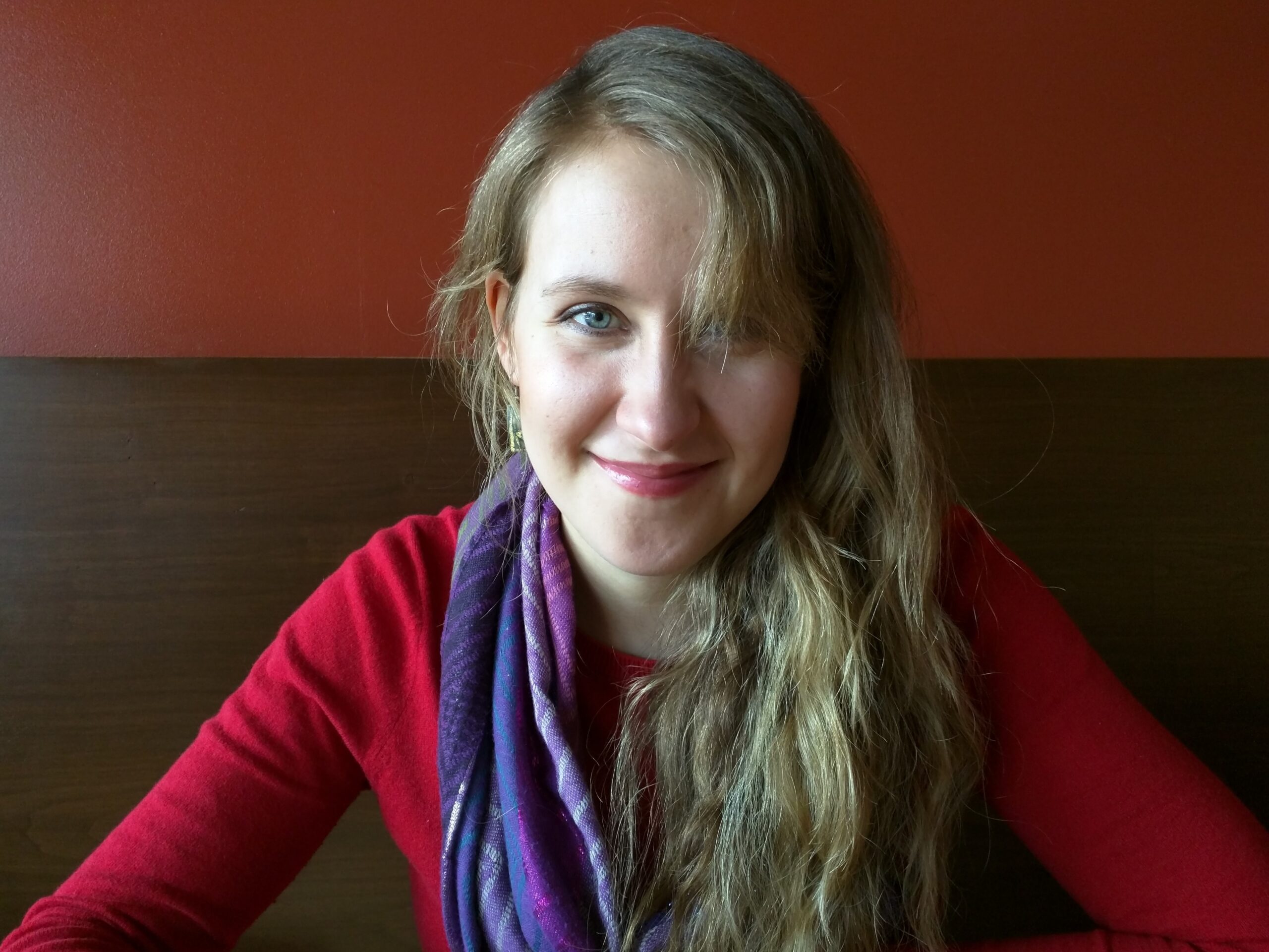 Close-up of Nicki Youngsma smiling while wearing a red sweater with a purple scarf around her neck.