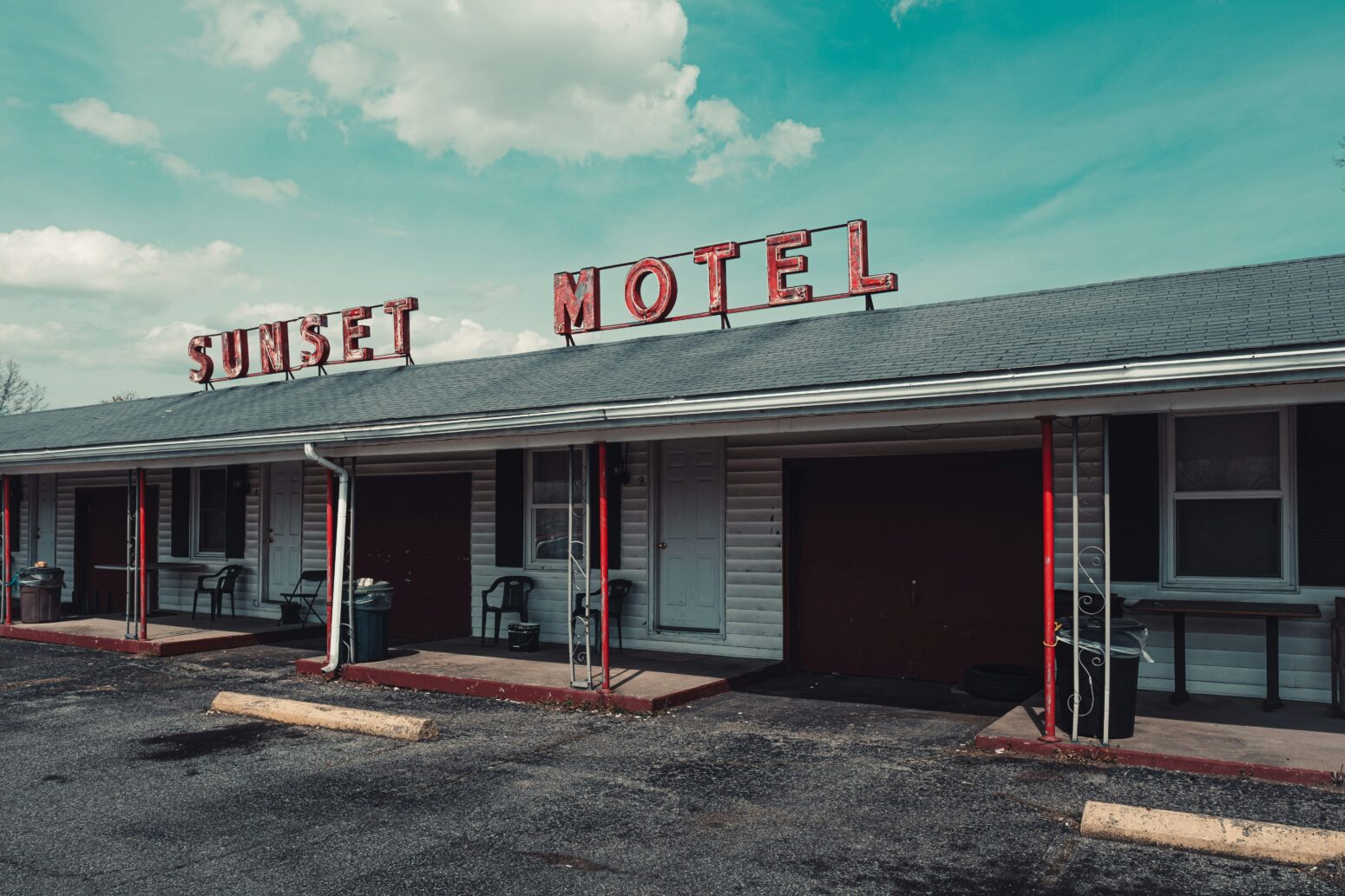 Exterior of the Sunset Motel. The name of the motel is spelled out in caps letters on the roof of the building, which is dilapidated.