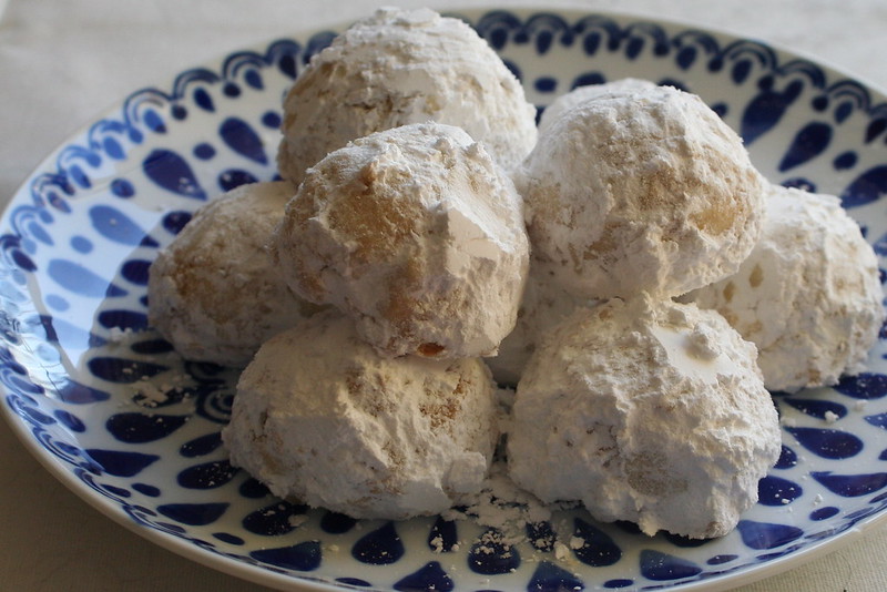 Cookie balls with powdered sugar on them, on a blue and white plate