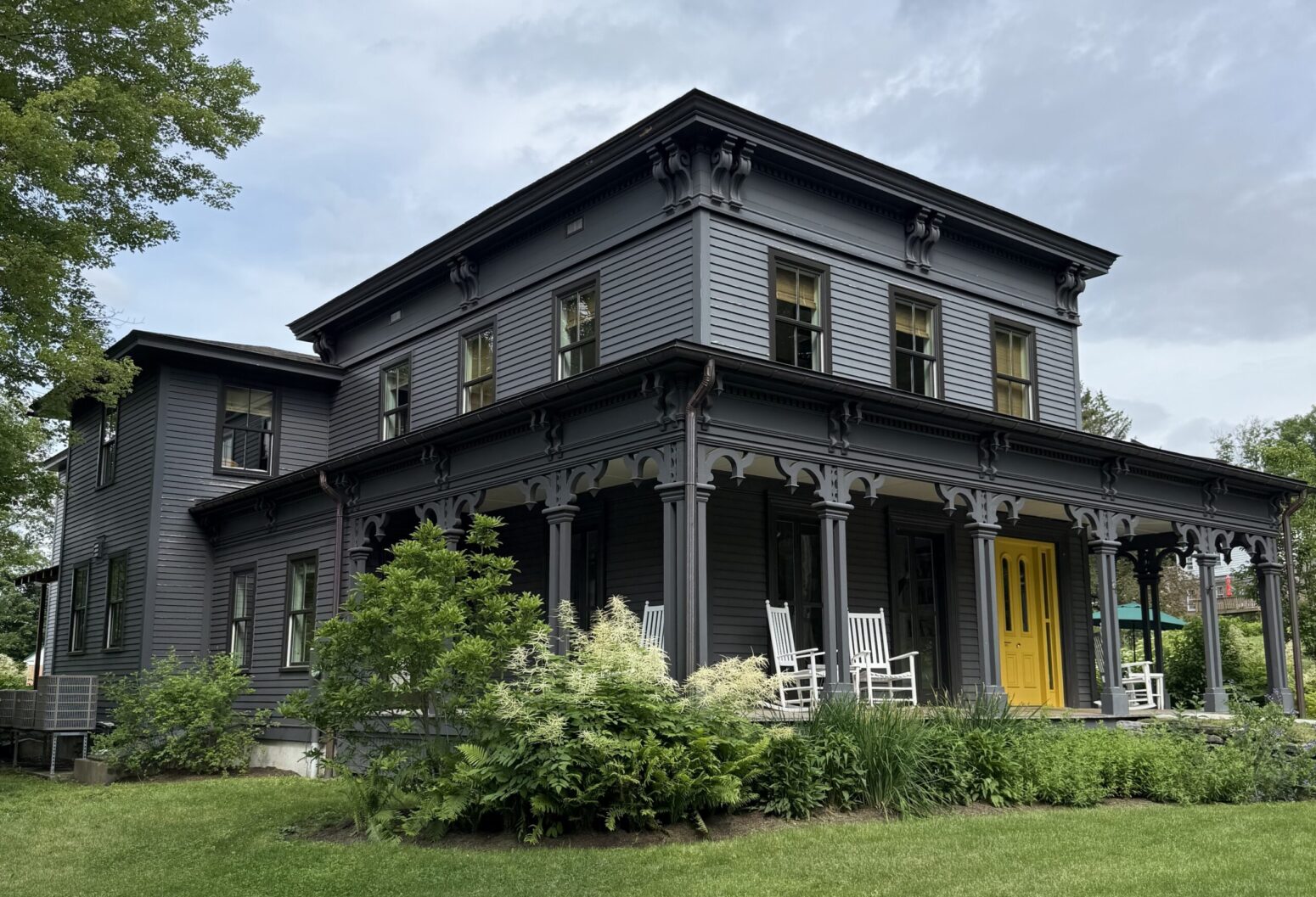 Prospect Street Writer's House, a two-story building with dark grey walls and a bright yellow door.