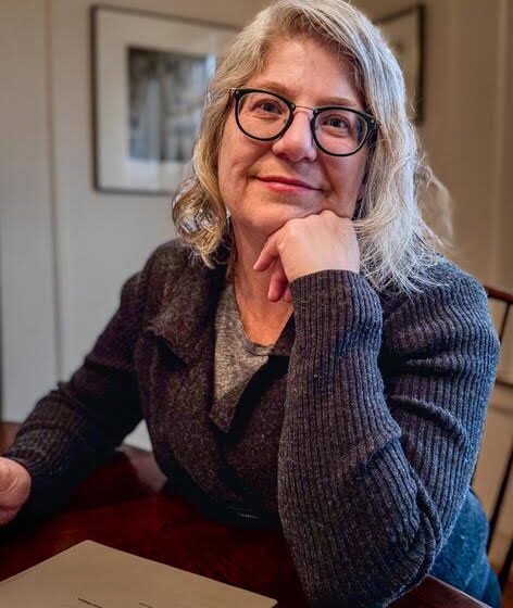 A white woman with glasses and medium-length gray hair.