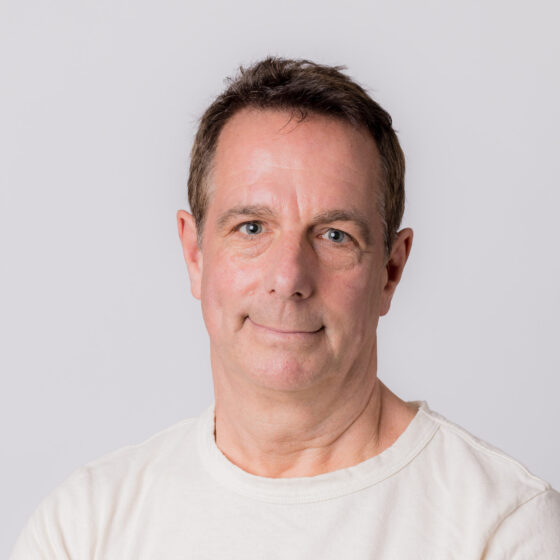 A white man with short dark hair in a white T-shirt