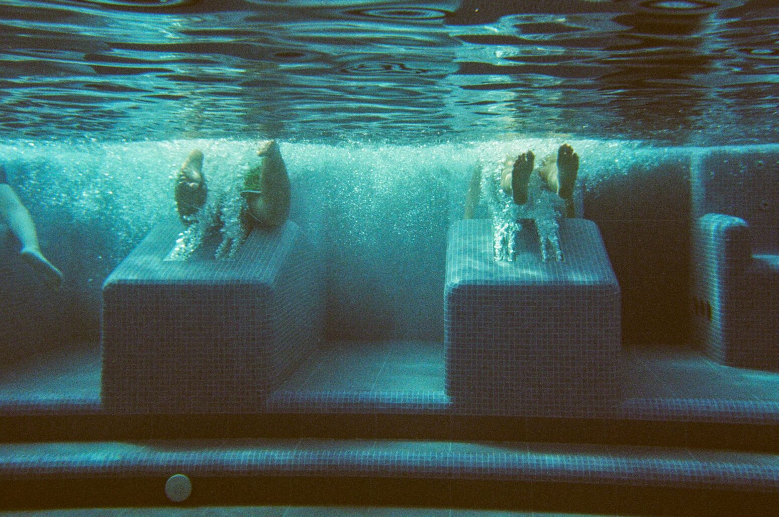 An underwater shot in the swimming pool with the legs of swimmers.