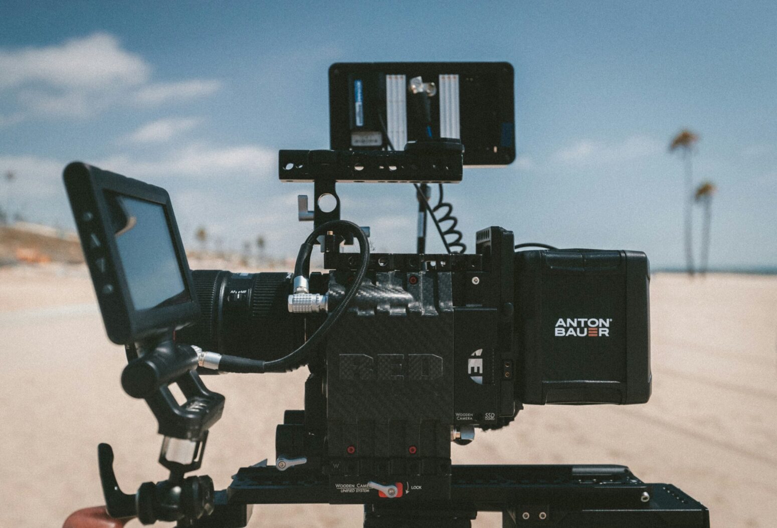 An elaborate video camera setup with monitor and cords. Blurred in the background is a beach scene