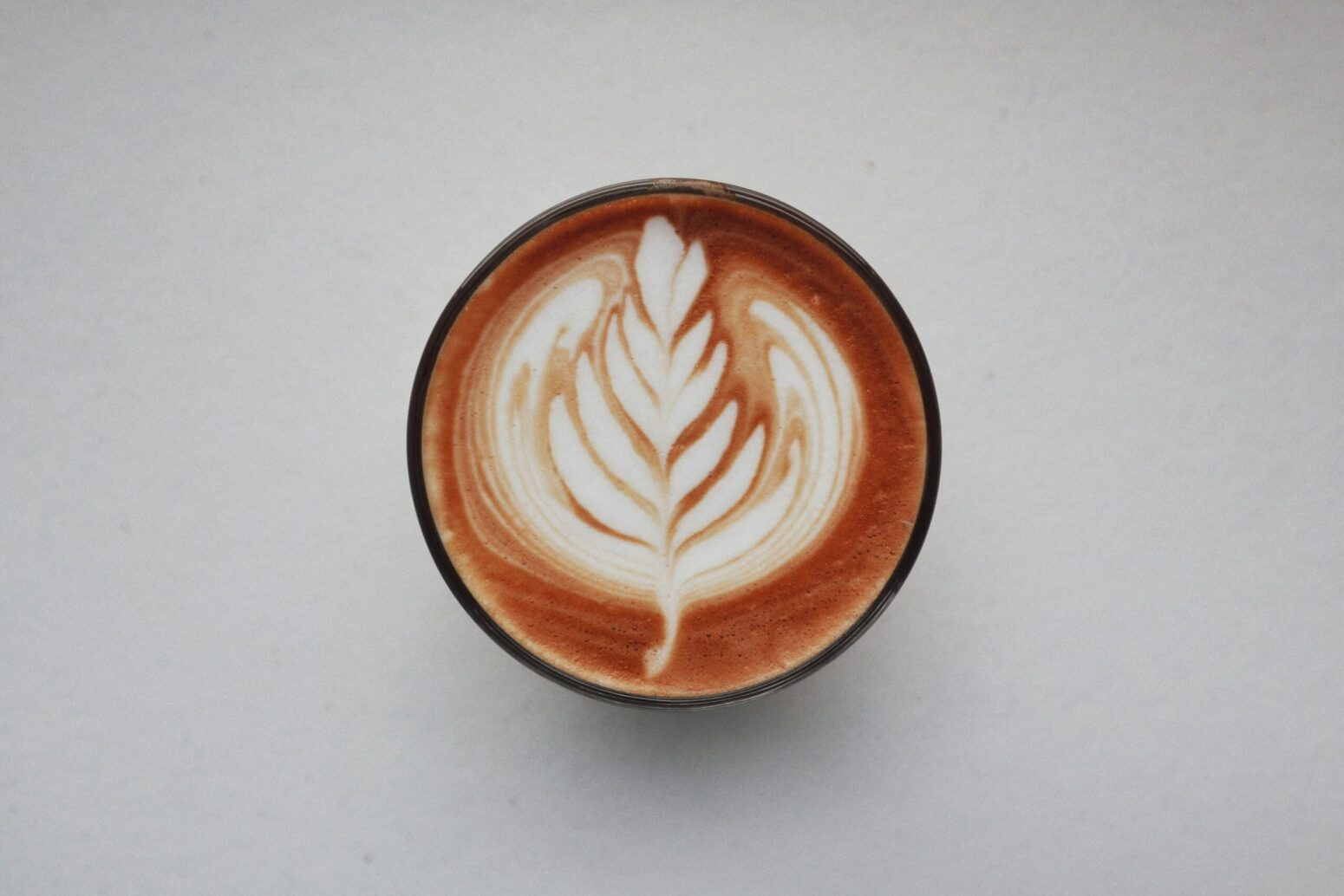 From above a latte with a tree shape with a heart at a top in the foam