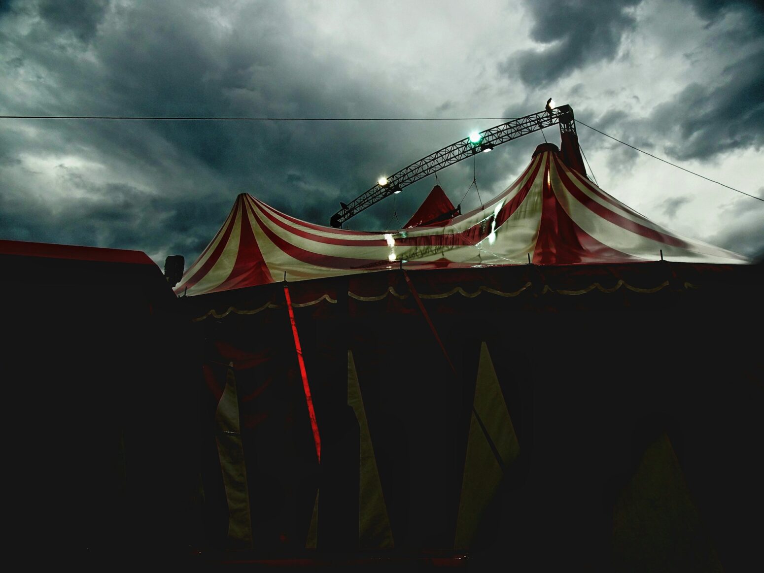 A red-and-white striped circus tent sits pitched under a gloomy sky