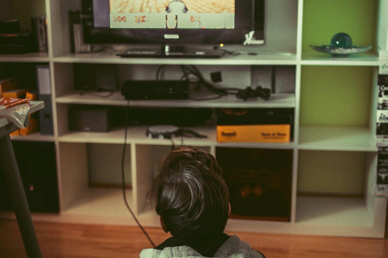 A little boy sitting on the floor, watching TV