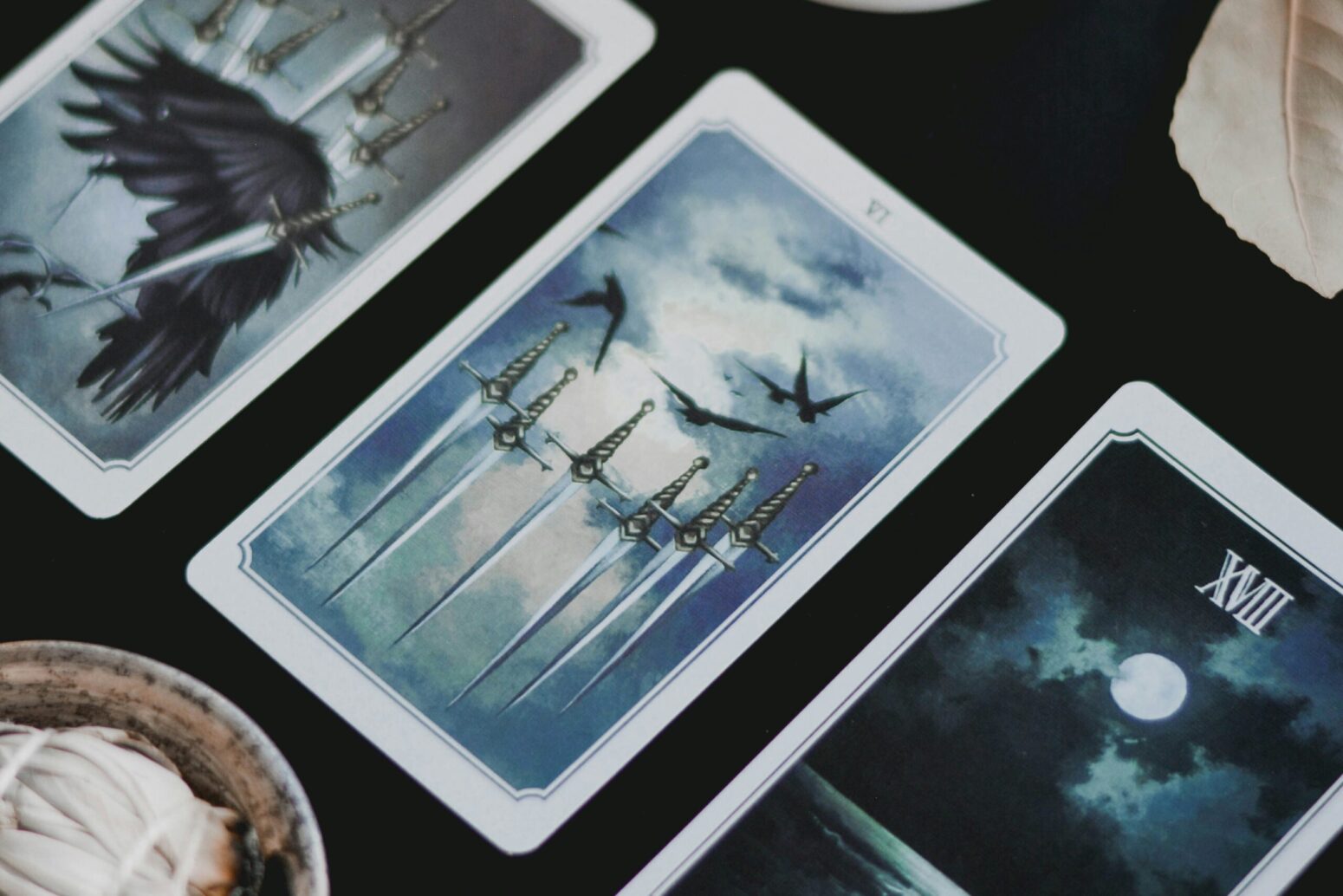 A line of tarot cards on a black table, the middle of which depicting multiple swords.