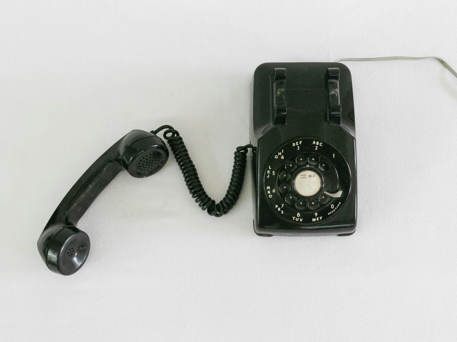 A black rotary phone sitting on a white background
