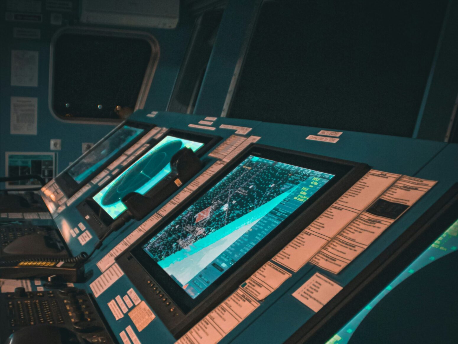 A panel of screens and controls on a spaceship. The panel is teal and covered in notes. The windows of the spaceship are black.