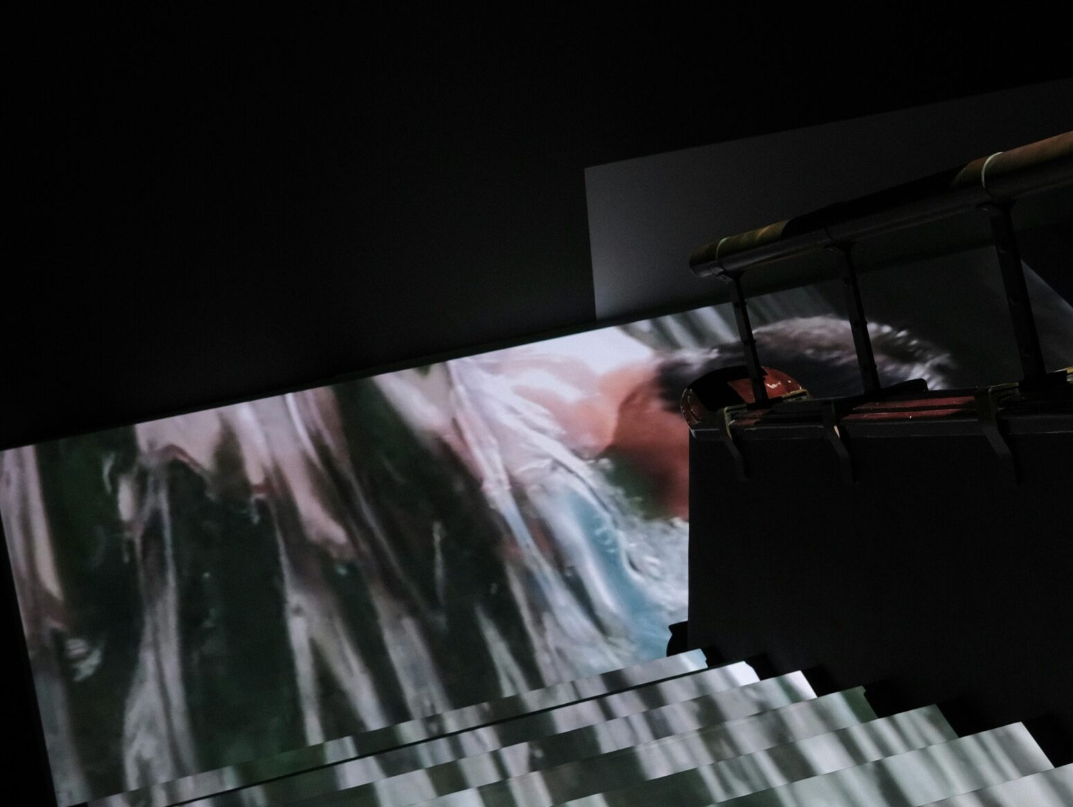A dark stairwell with a photograph of a man projected onto the floor.