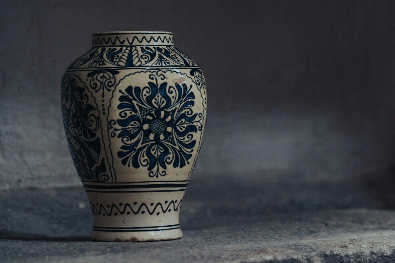 Two ornately decorated, blue-and-white urns, sitting on a stone shelf.