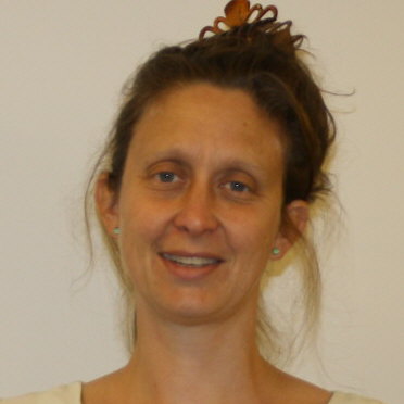 Linnea Paskow, a white woman with brown hair pulled up and held with a clip, smiles.