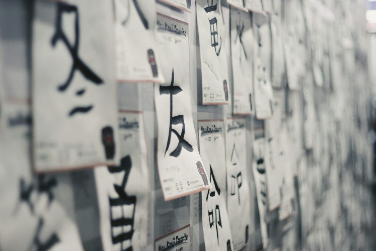 A wall of white notes posted on it, with calligraphy of kanji characters on each of them.