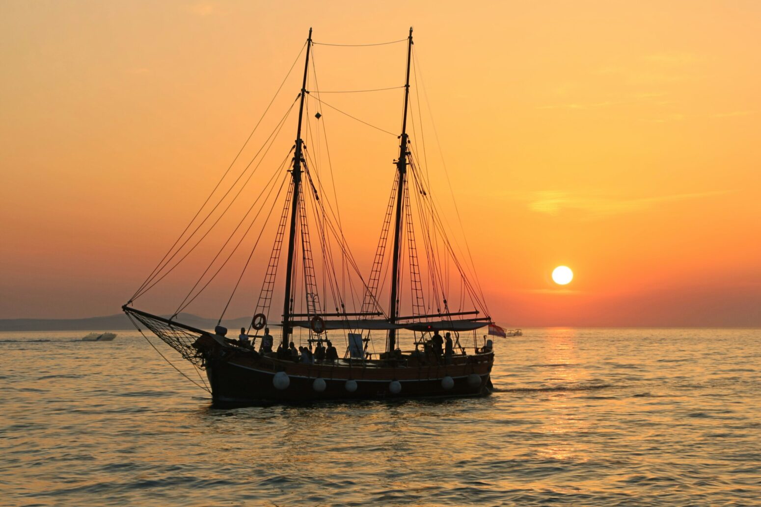 A silhouette of a ship at sea during sunset.