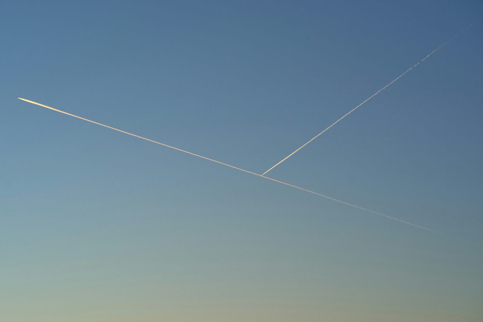 Two rockets streaking across a blue sky. One is to the northeast, the other is going toward the southeast.