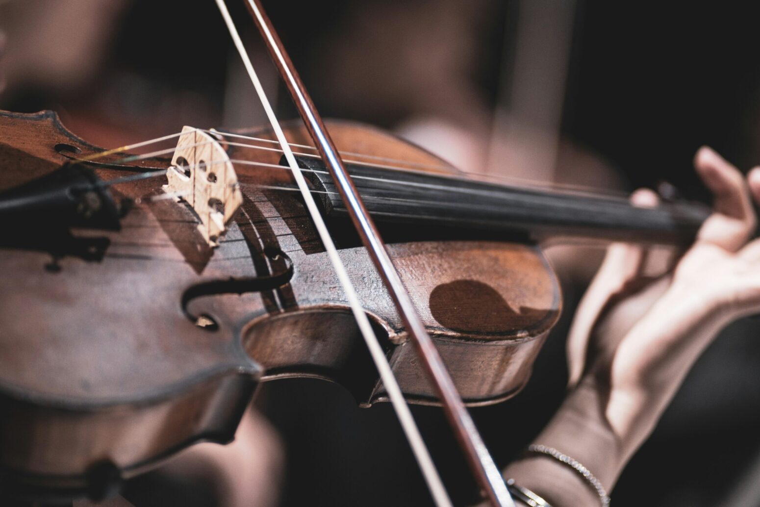 A violin being played by someone. The background is a blurred out stage