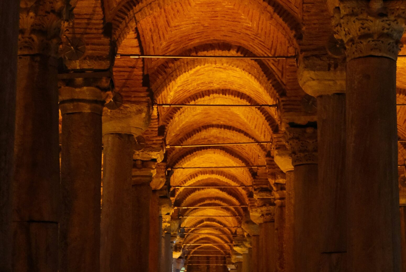 The stone arches and columns lit by yellow lighting of The Basilica Cistern in Istanbul, Turkey.