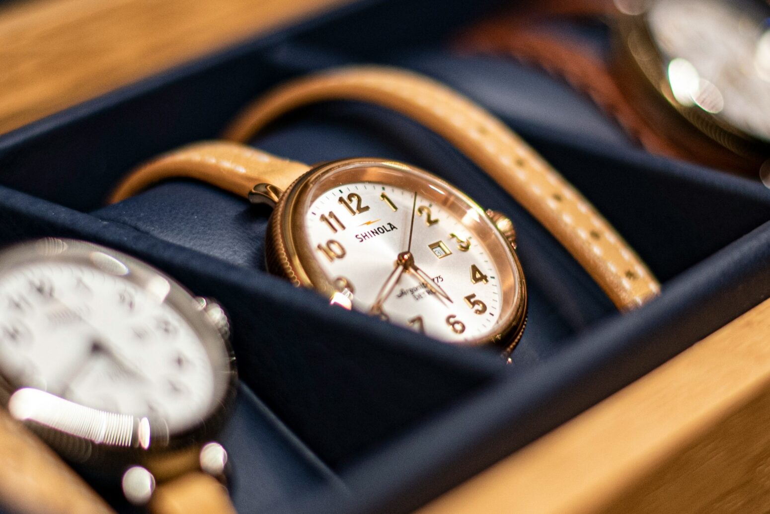 Three watches sit in a small, wooden display case.