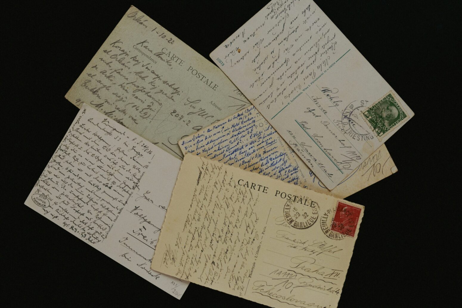 A small pile of old postcards on a black background.