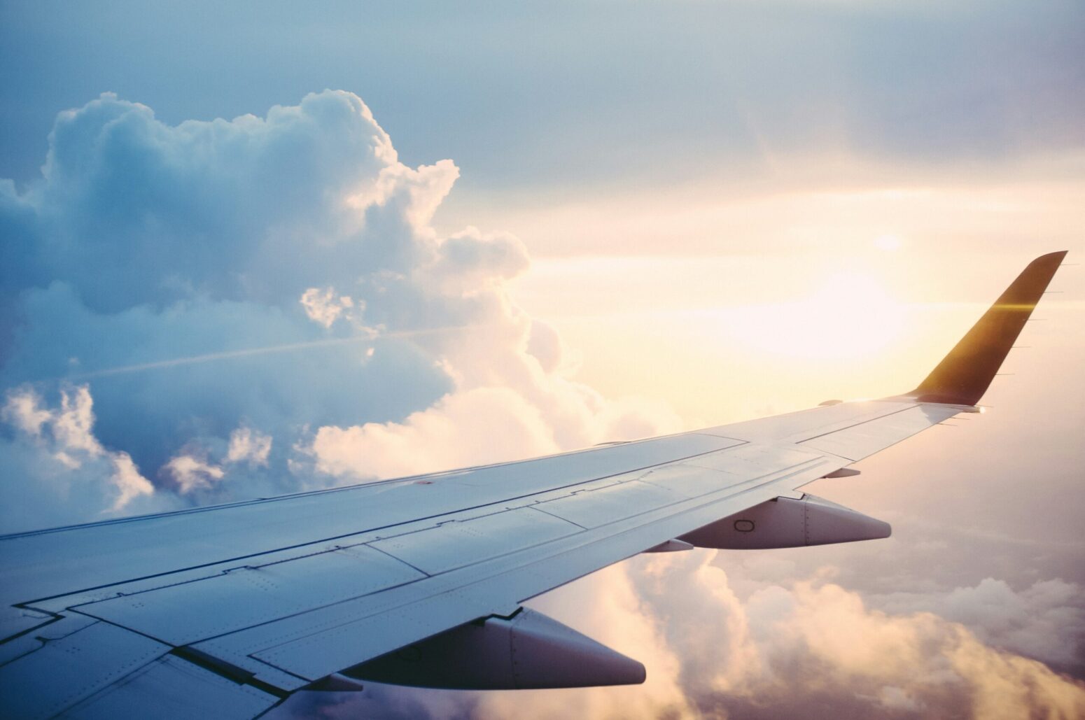 A view of the wing of a plane against the sky from the plane window.